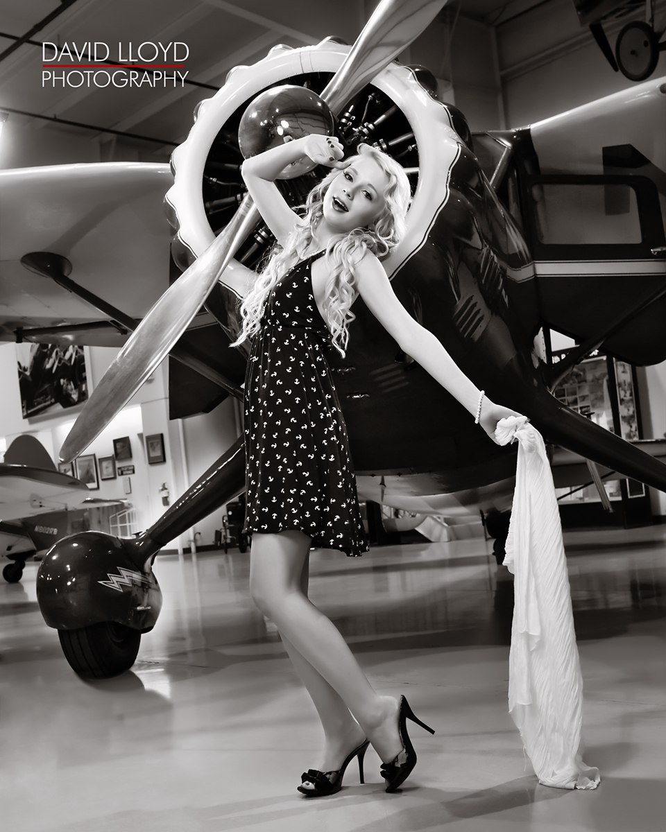black and white woman standing in front of old military plane posing with black and white dotted dress, photography, glamour shot, glamour photography atlanta 