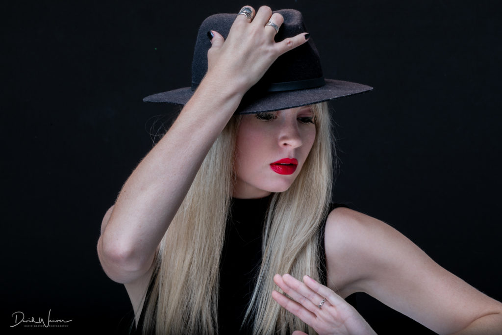 Model in black top hat puts her hand on head for a pose, portrait photography, fisheye connect, photography workshop, model workshop, studio workshop, photography studio, studio lighting, photoplex studios, lighting skills, photography
